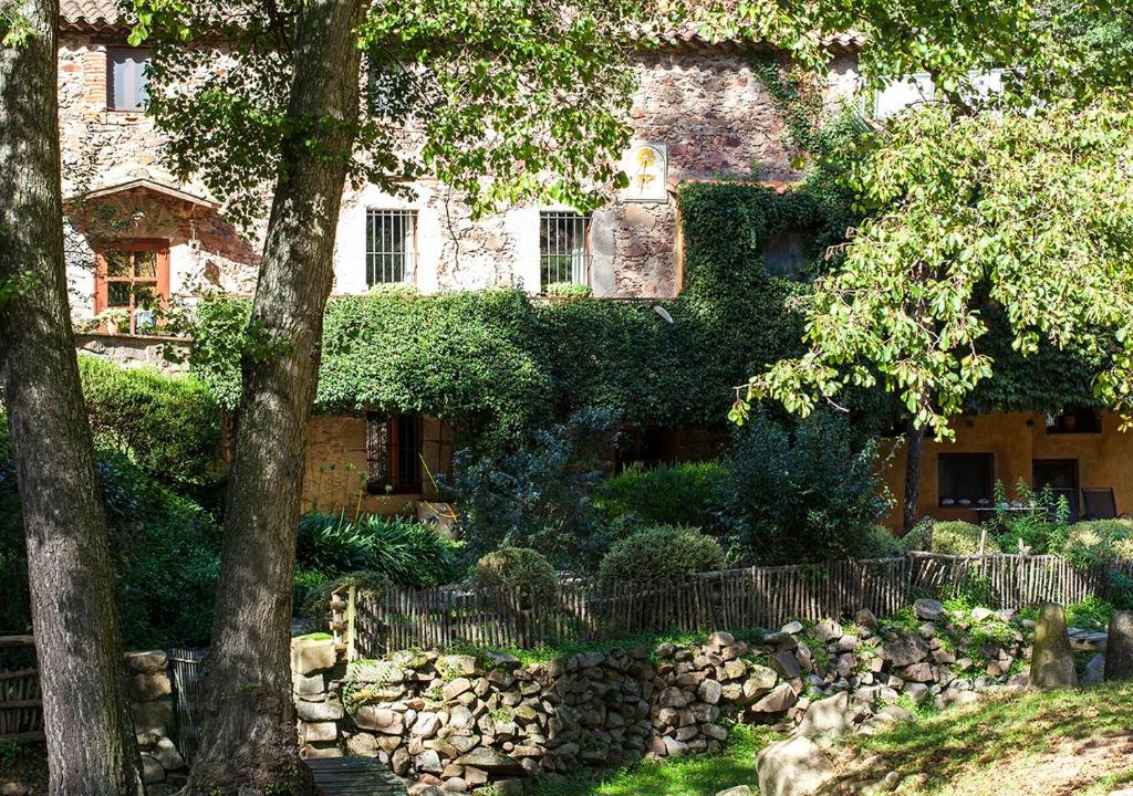 un edificio con una valla de piedra frente a un jardín en Masía El Moli de Can Aulet, en Arbúcies
