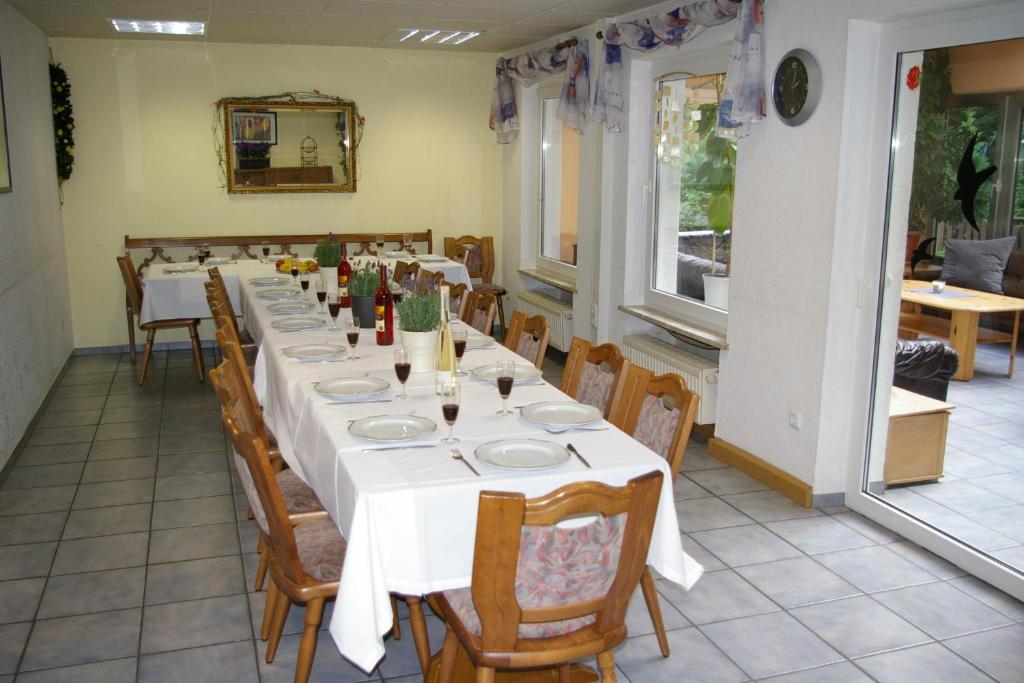 un comedor con una mesa larga con mesas y sillas blancas en Ferienhaus Waldrand, en Ulmen