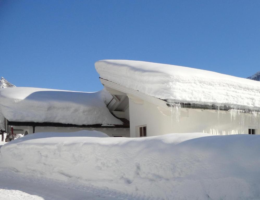 una casa cubierta de nieve con carámbanos. en Haus Bitschnau, en Wald am Arlberg