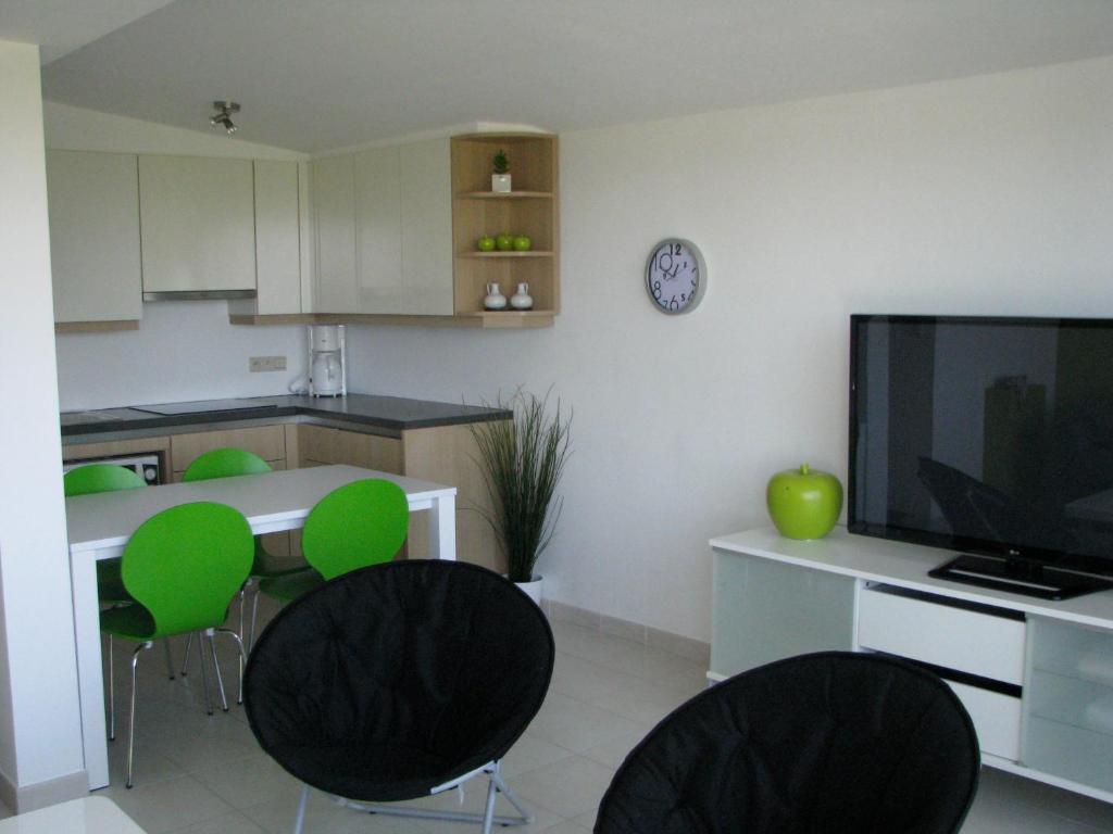een keuken met groene stoelen en een tafel met een tv bij Appartement Iris in De Haan