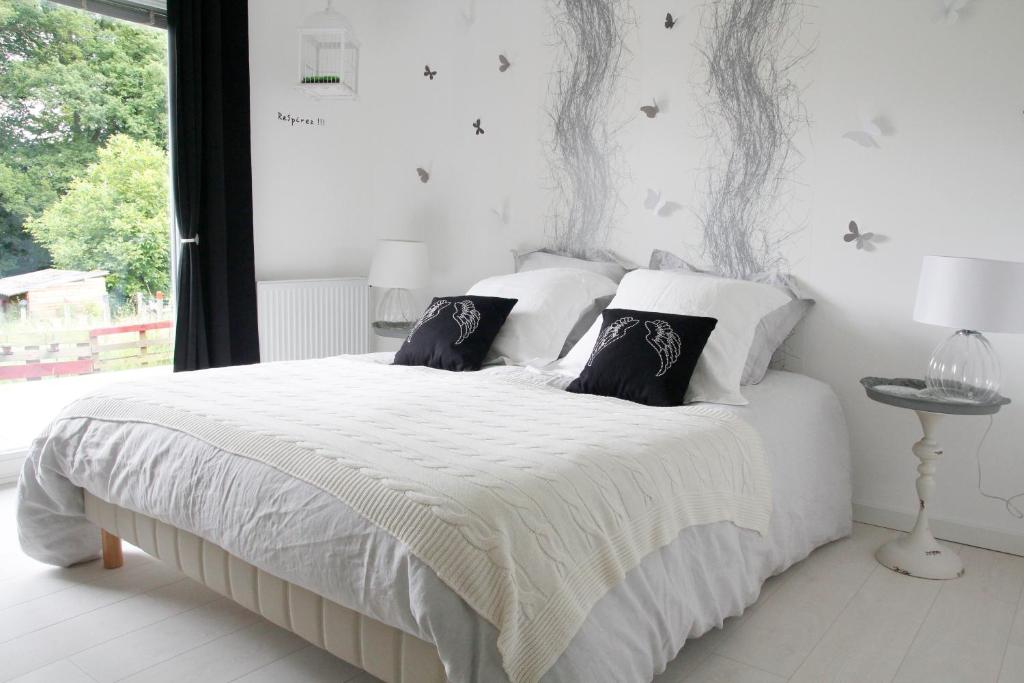 a bedroom with a white bed with black and white pillows at Chambres d'hôtes Souffle Nature in Montenois