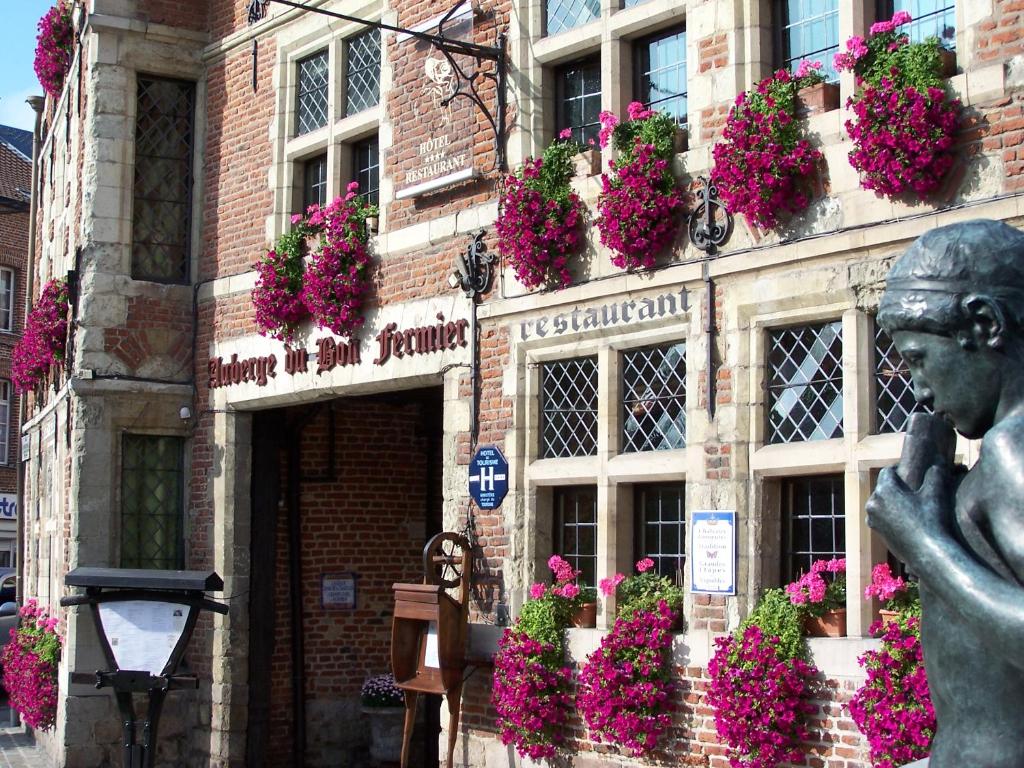 une statue devant un bâtiment fleuri dans l'établissement Auberge Du Bon Fermier, à Valenciennes