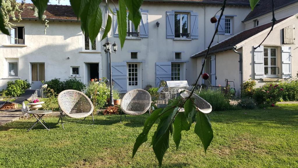 une cour avec trois chaises et une maison dans l'établissement Les Jardins de la Tuilerie, à Jouarre