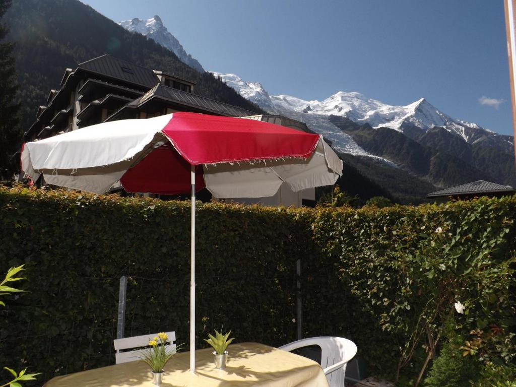 una mesa con una sombrilla roja y blanca y montañas en 2 Pièces+Terrasse CHAMONIX CENTRE en Chamonix-Mont-Blanc