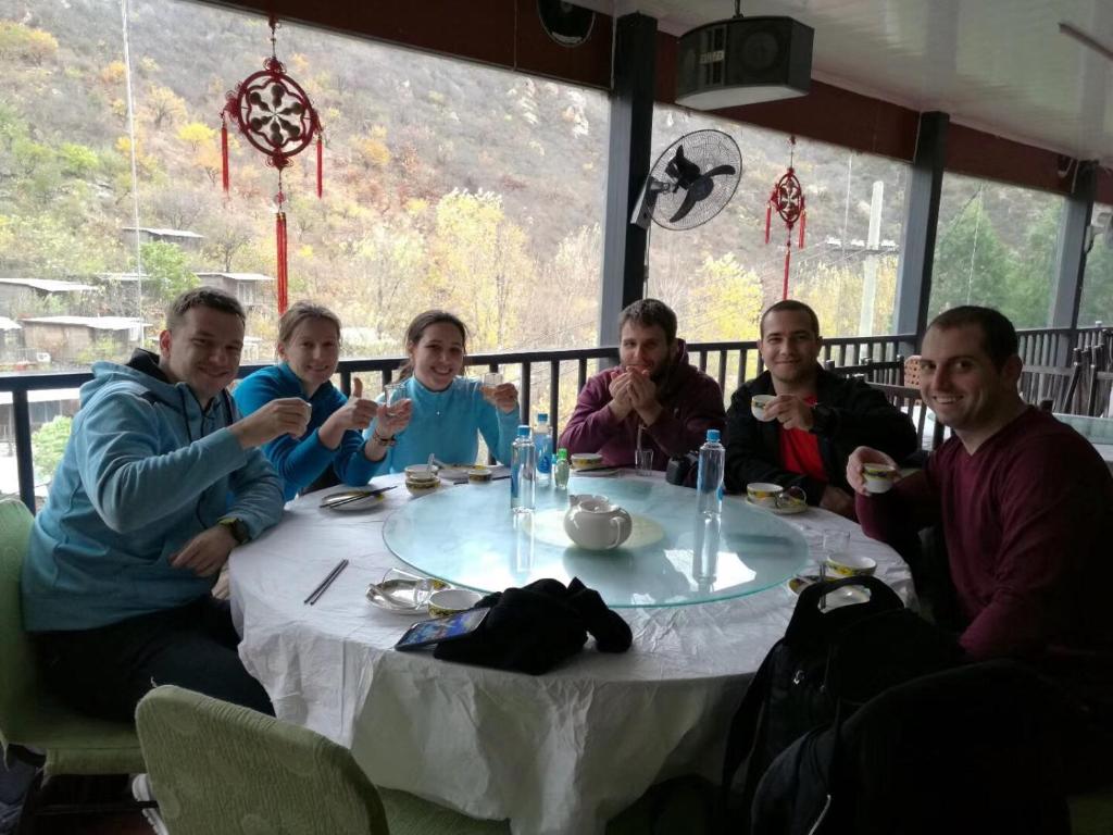 un grupo de personas sentadas alrededor de una mesa en Huangyaguan Great Wall Li Bo Home Hotel, en Jixian