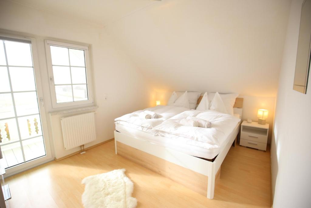 a white bed in a room with two windows at Villa Hasi in Aich