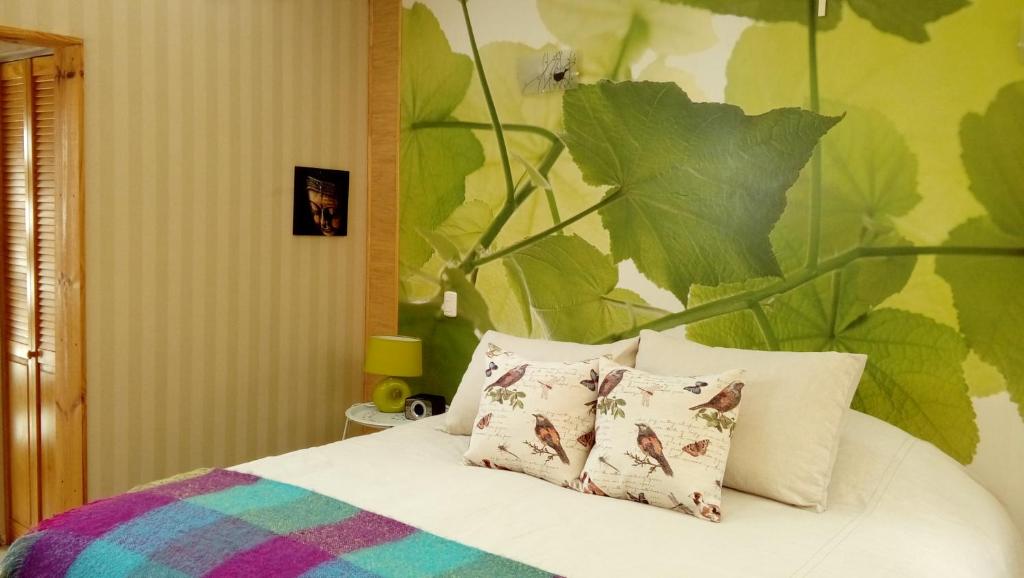 1 cama con 2 almohadas y una gran pared de hojas en Organica Lodge Spa en Vicuña
