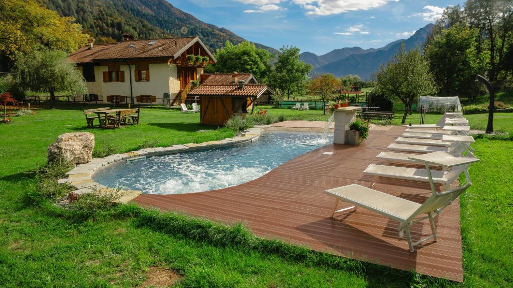 einen Pool mit einer Terrasse und Stühlen sowie ein Haus in der Unterkunft Rustico Pastoria in Lenzumo di Concei