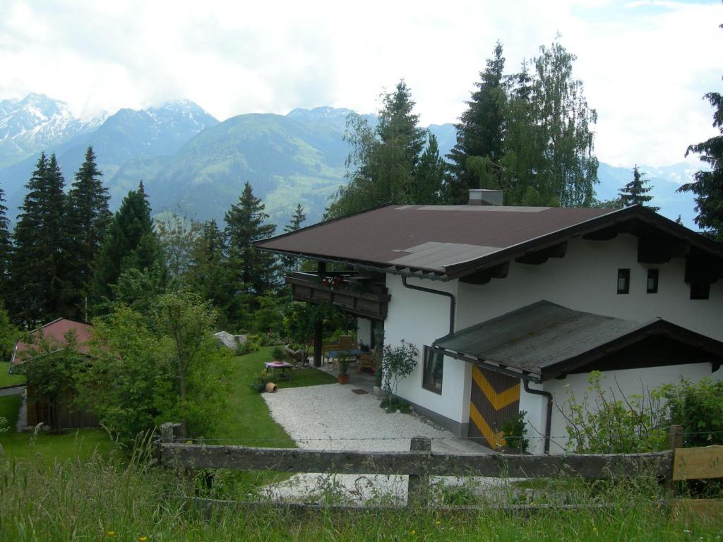 ein Haus mit einem Zaun davor mit Bergen in der Unterkunft Ferienwohnung Holzer Maria in Mittersill