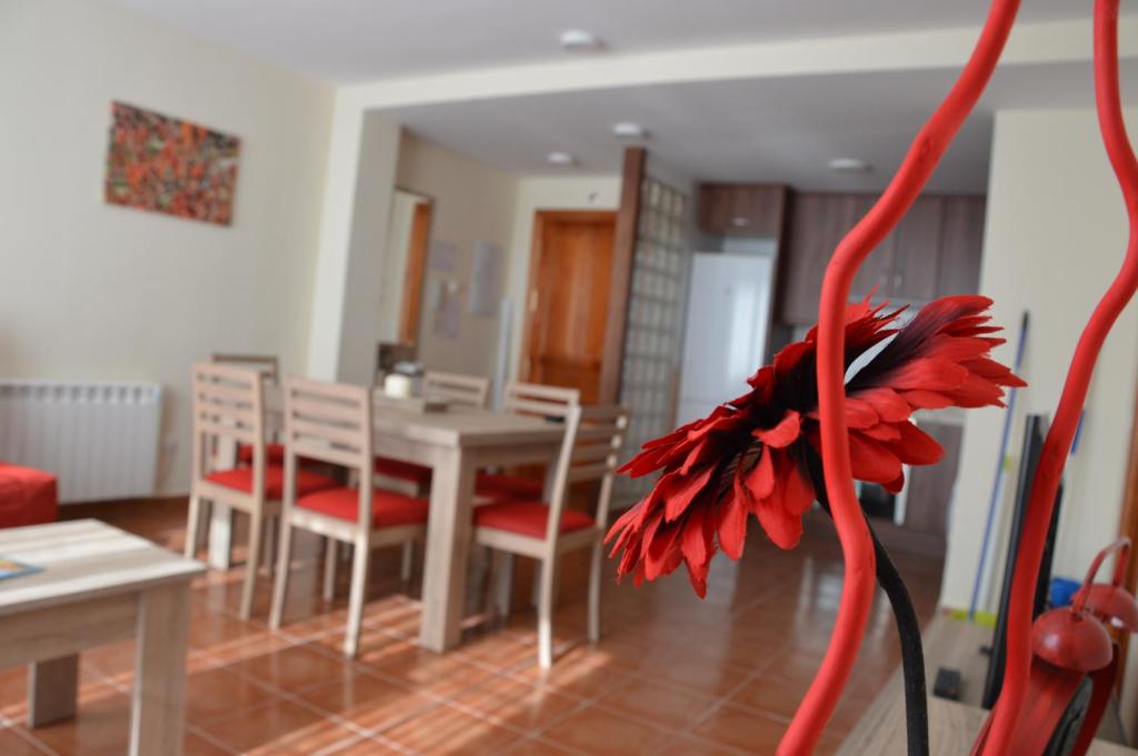 un soggiorno con tavolo, sedie e un fiore rosso di Vivienda Salvia a Nogueruelas