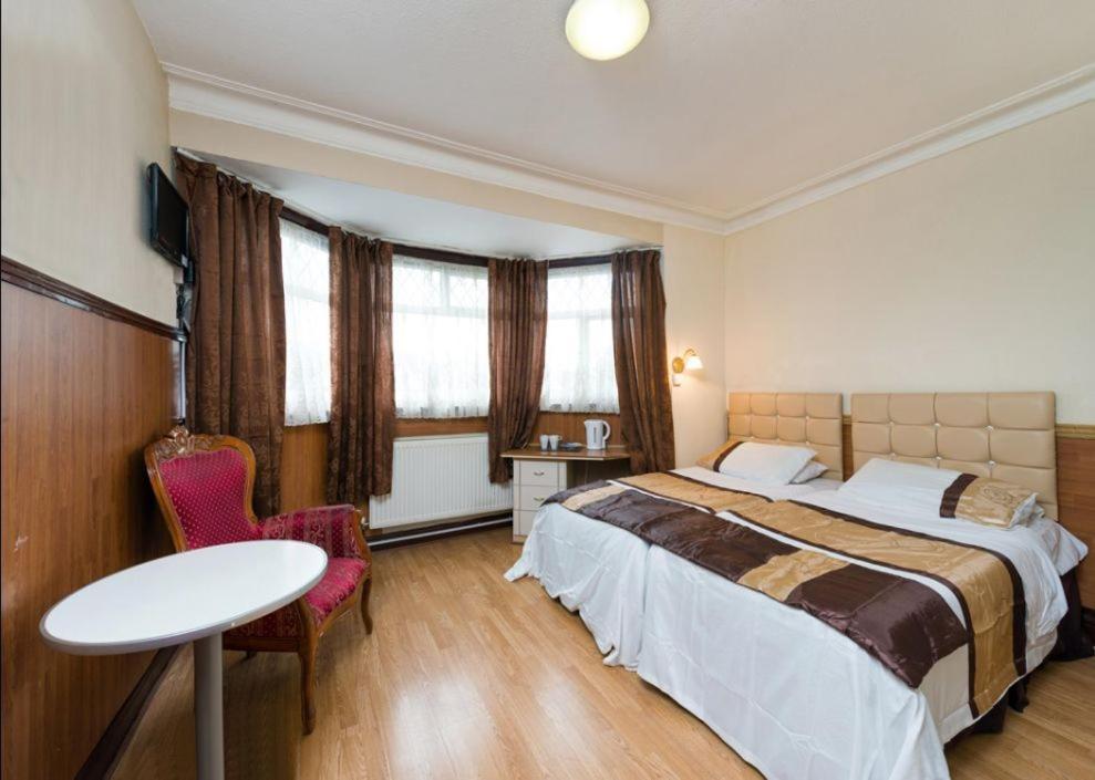 ロンドンにあるゴールダーズ グリーン ホテルのベッド、テーブル、椅子が備わるホテルルームです。