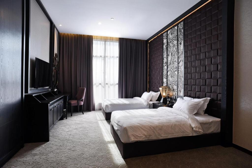 a hotel room with two beds and a flat screen tv at Vangohh Eminent Hotel & Spa in Bukit Mertajam