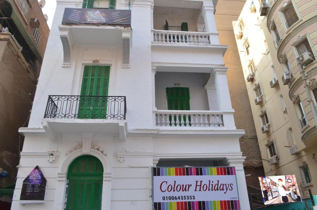 a white building with green windows and a sign on it at Colour Holidays in Cairo