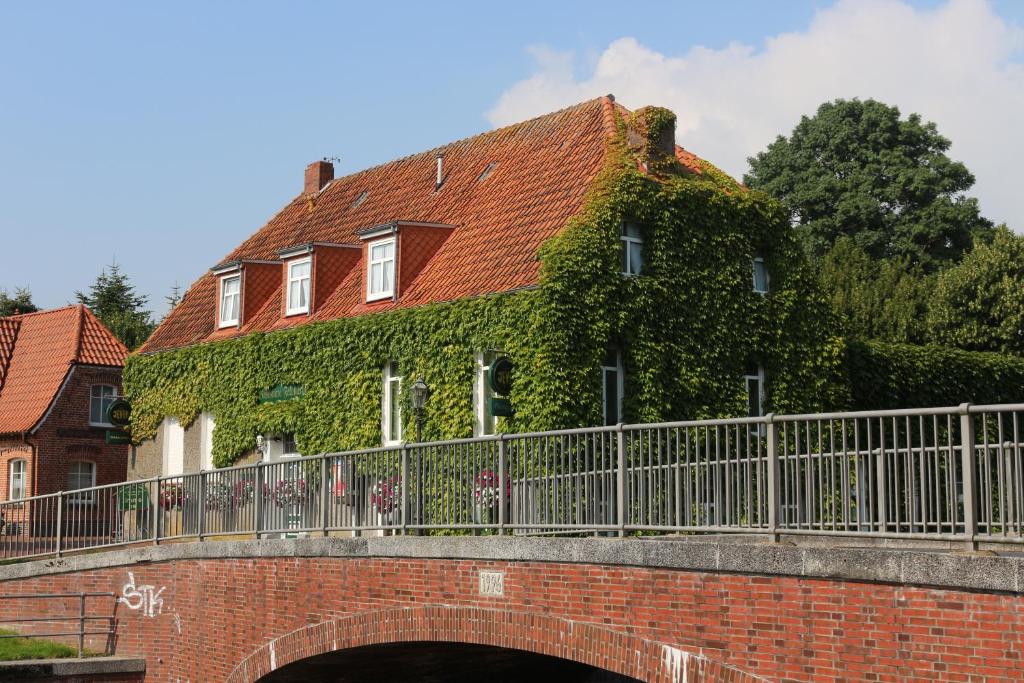 una casa cubierta de hiedra en un puente de ladrillo en Gaststätte Feldkamp, en Hinte