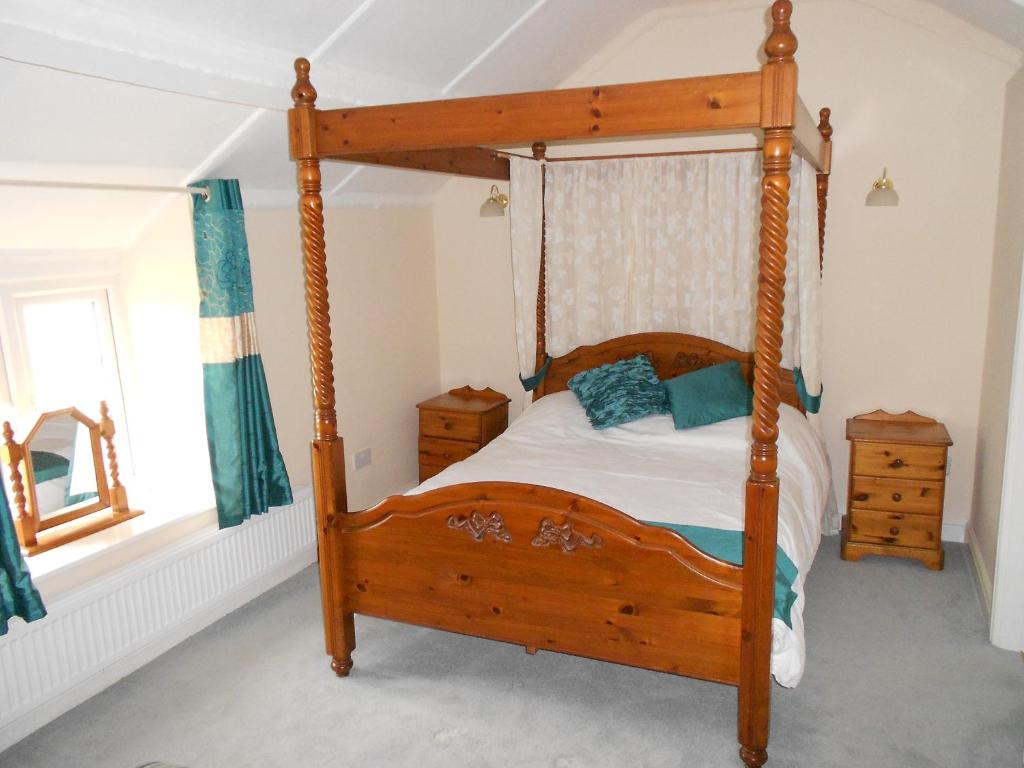 The Glan Yr Afon Inn في هوليويل: غرفة نوم بسرير خشبي مع اطار خشبي