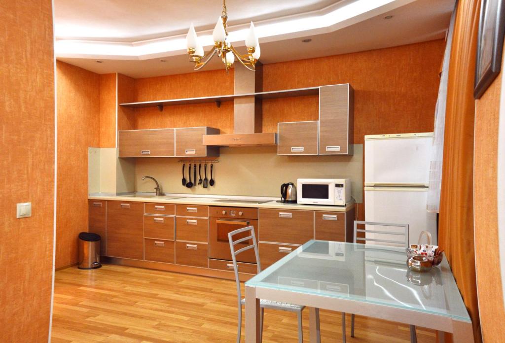 a kitchen with wooden cabinets and a table and a refrigerator at SutkiUfa Рихарда Зорге 70/2.1 in Ufa