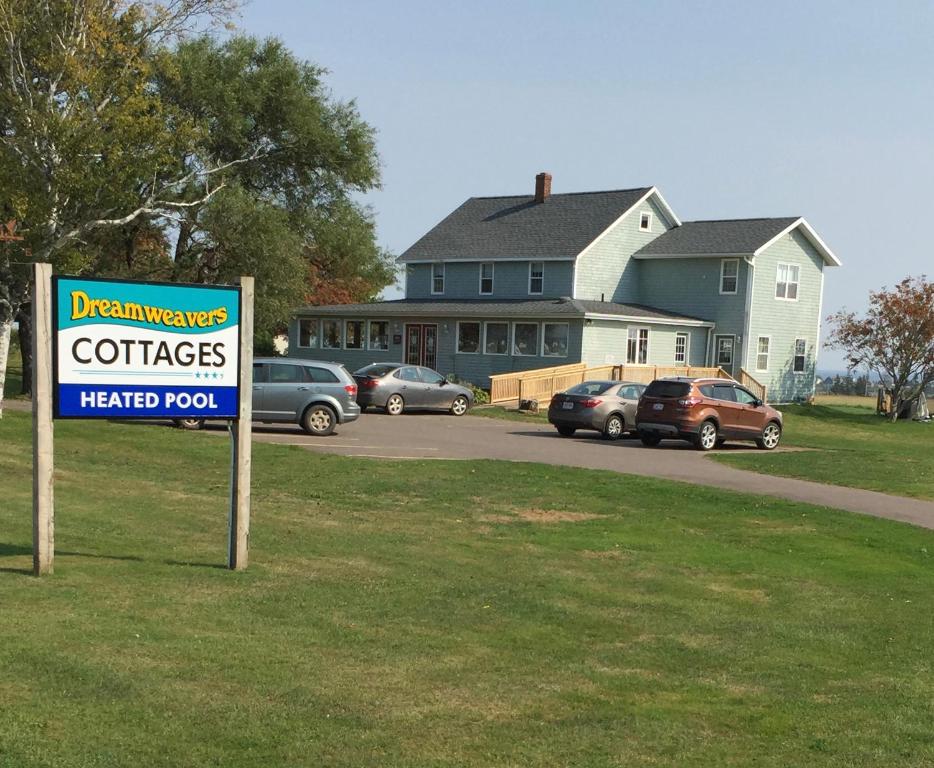 a sign in front of a house with cars parked at Dreamweavers Cottages and Home Place Vacation Home in Rustico