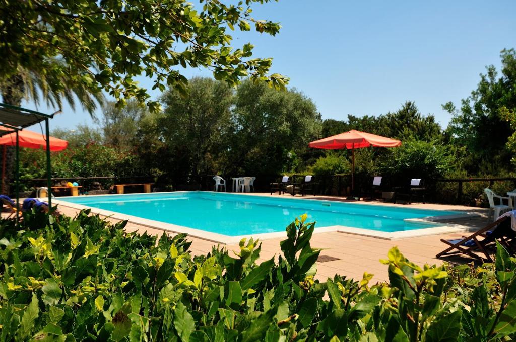a beach area with a pool, chairs, and a blue umbrella at Hotel Fuile 'E Mare in Cala Liberotto