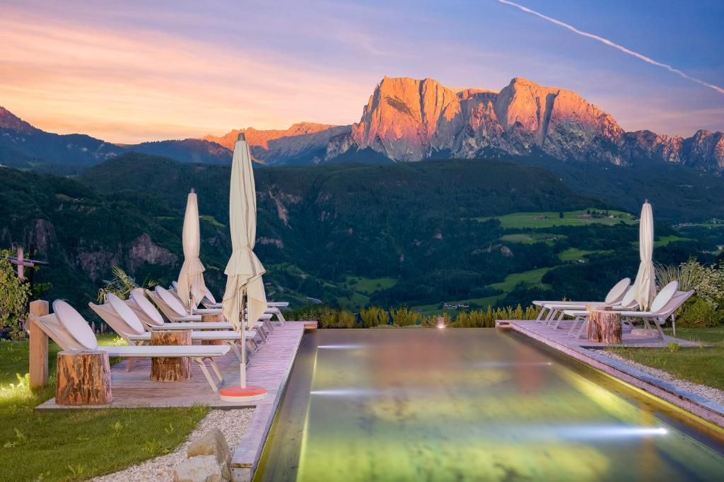 a group of chairs with umbrellas and a pool at Aktiv&Bio Pennhof in Barbiano