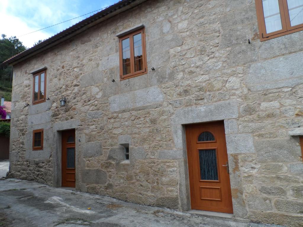 Casa Barqueiro في Outes: مبنى حجري بأبواب بنية اللون ونوافذ