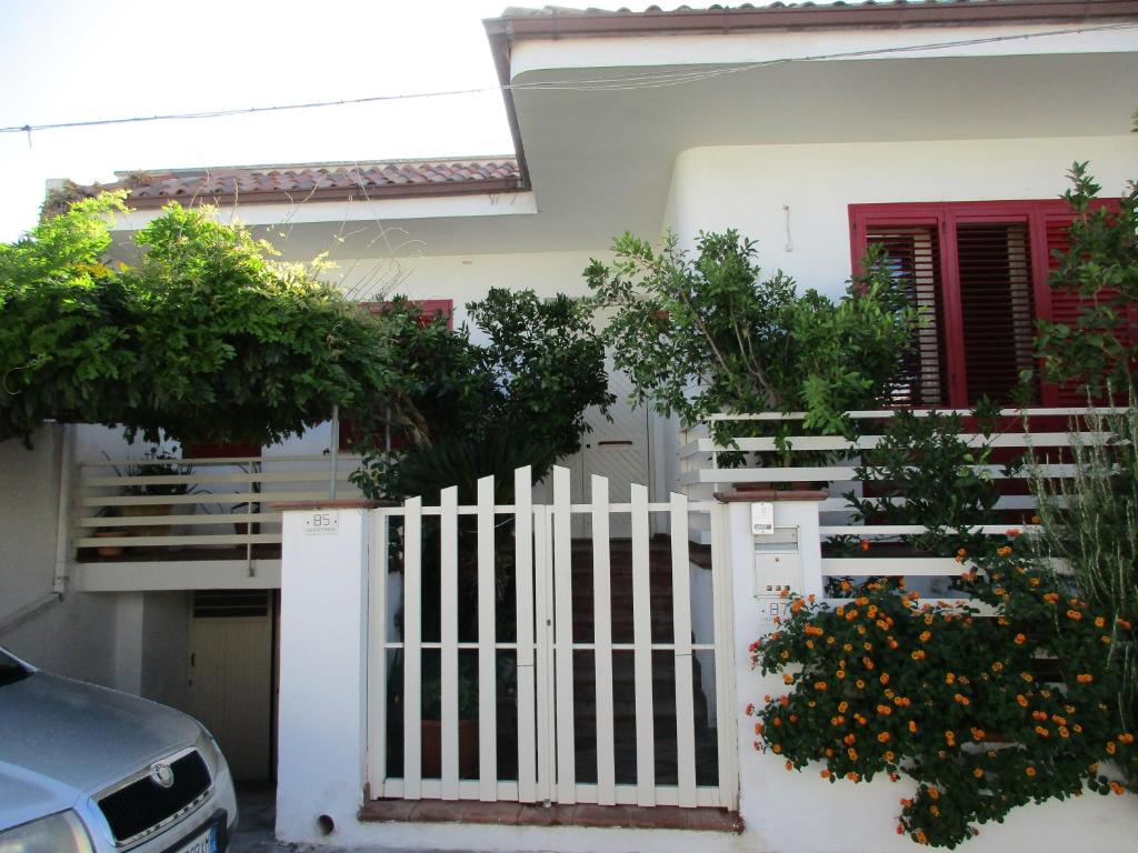 a white fence in front of a house with trees at Casa Dario in Melissano