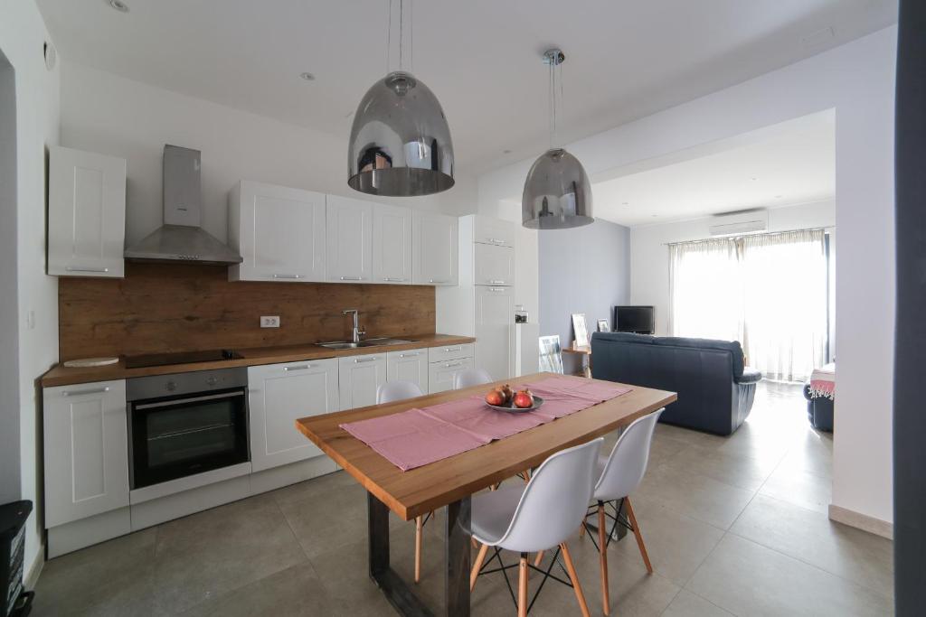 a kitchen with a wooden table and white cabinets at Lemon house in Komin