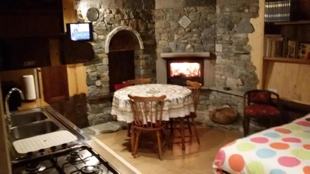 cocina con mesa y chimenea de piedra en Taverna Semon, en Verrayes