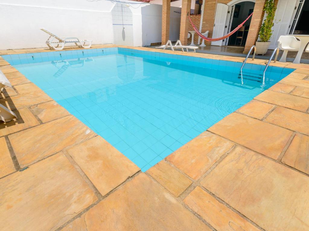 a swimming pool with a wooden floor and blue water at Pousada Morada da Prainha in Caraguatatuba
