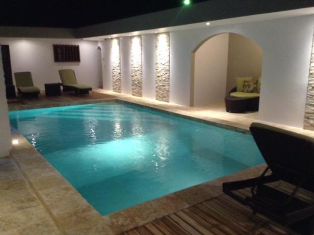 a large swimming pool in a room with chairs and a couch at Hotel Flor De Sarta in León