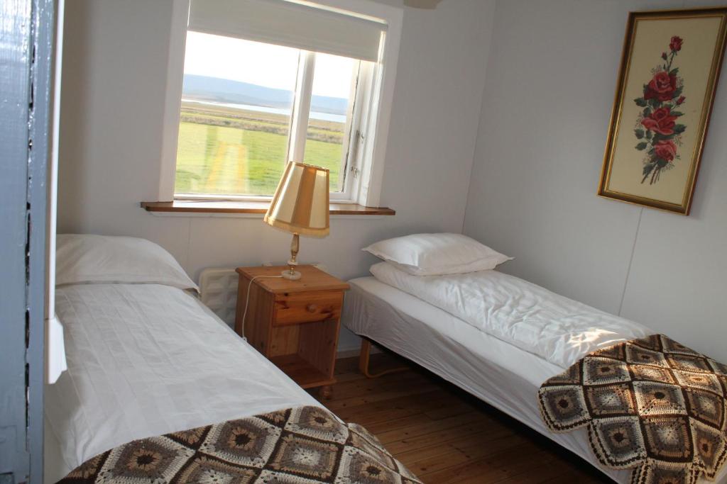 two beds in a small room with a window at Midhop guesthouse in Þingeyrar