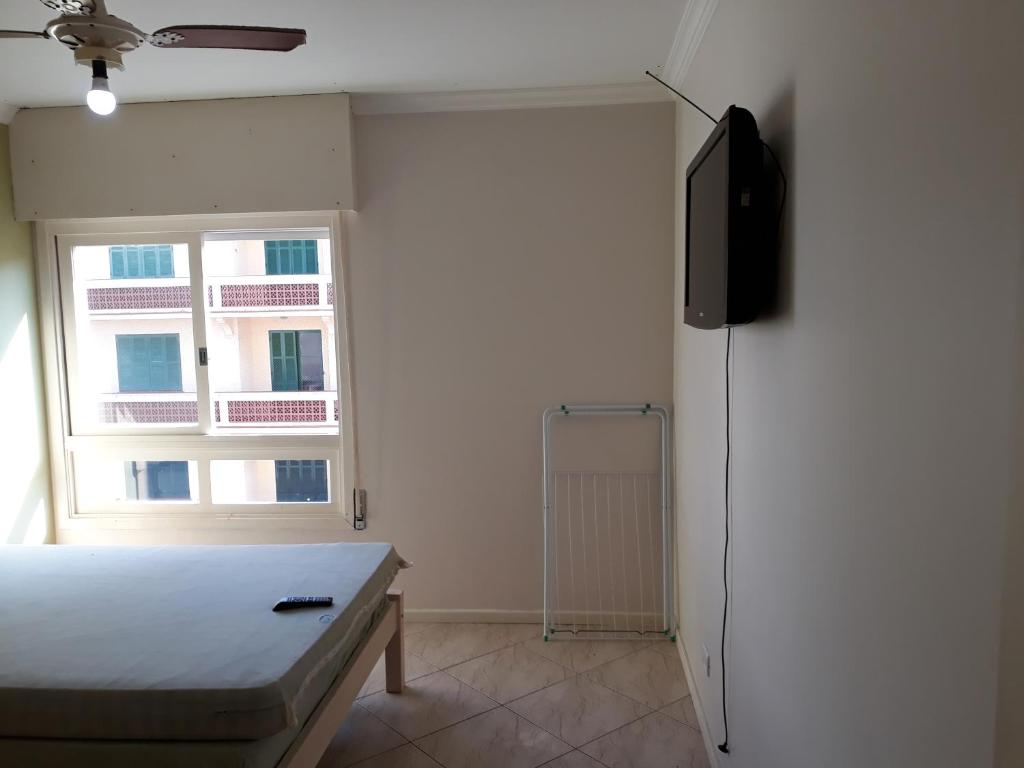 una camera da letto con un letto, una tv e una finestra di Edifício Torre de Prata a Torres
