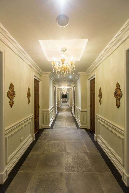 A long, formal hotel corridor with chandeliers and decorative wall panels.