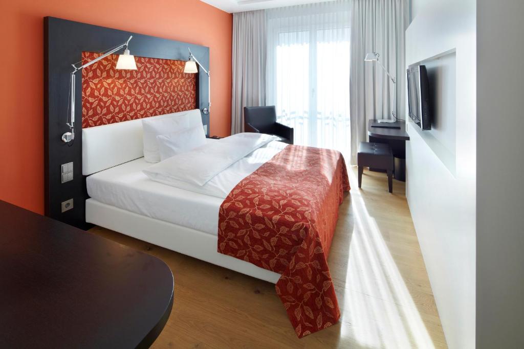 a hotel room with a bed and a desk at Parkhotel Stuttgart Messe-Airport in Leinfelden-Echterdingen