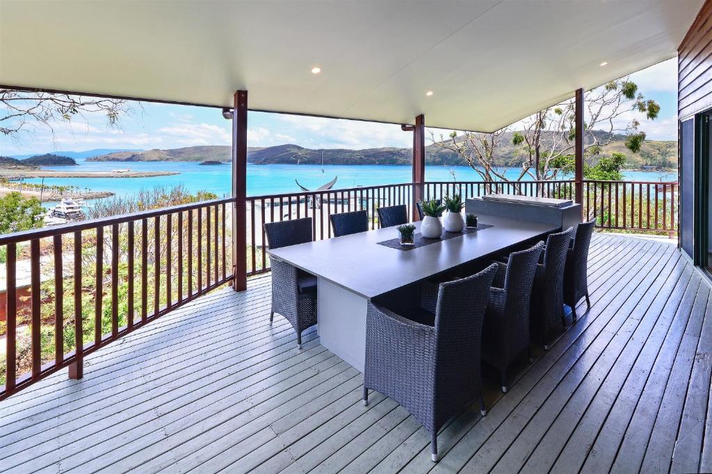 a large deck with a table and chairs on it at Casuarina Cove Apartments in Hamilton Island