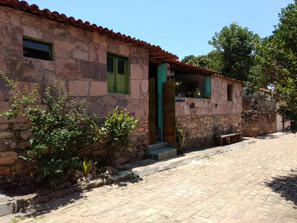 a stone house with green doors and a brick driveway at Pousada Orquídea in Igatu