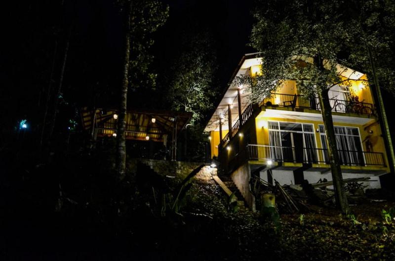 馬特萊的住宿－river edge bungalow，夜晚点燃的房子,设有阳台