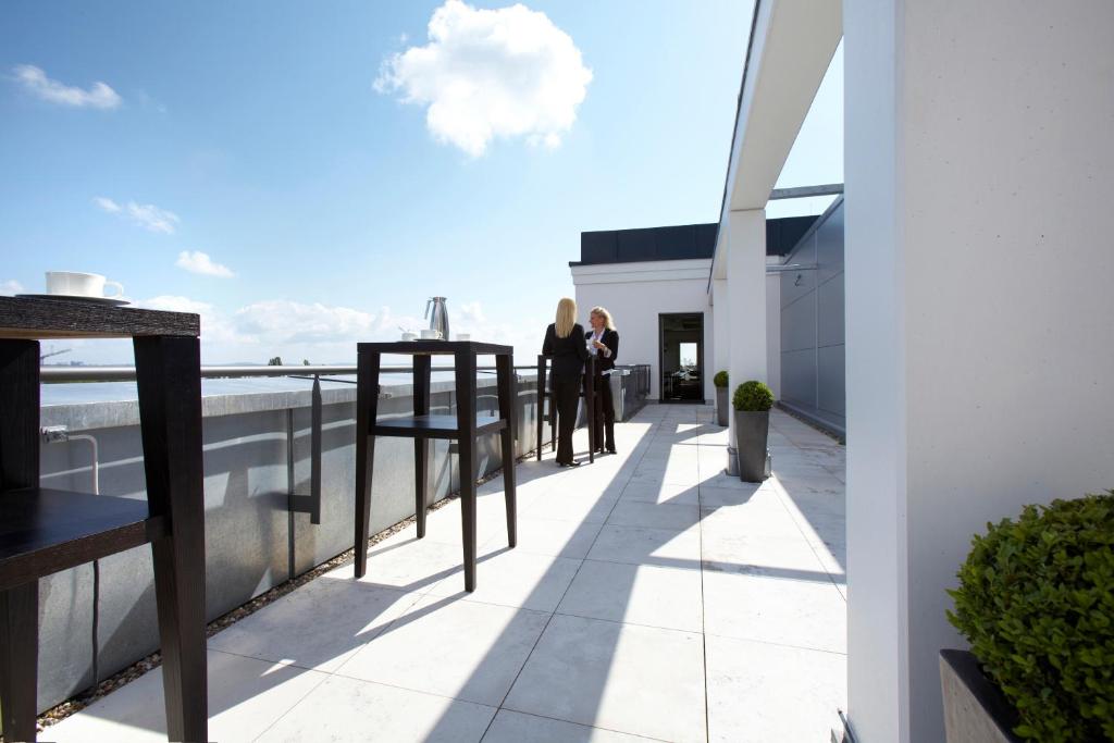 two people standing on a balcony looking out at the ocean at Parkhotel Stuttgart Messe-Airport in Leinfelden-Echterdingen