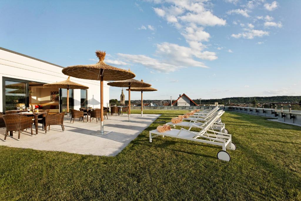 a row of lounge chairs and umbrellas on the grass at Parkhotel Stuttgart Messe-Airport in Leinfelden-Echterdingen