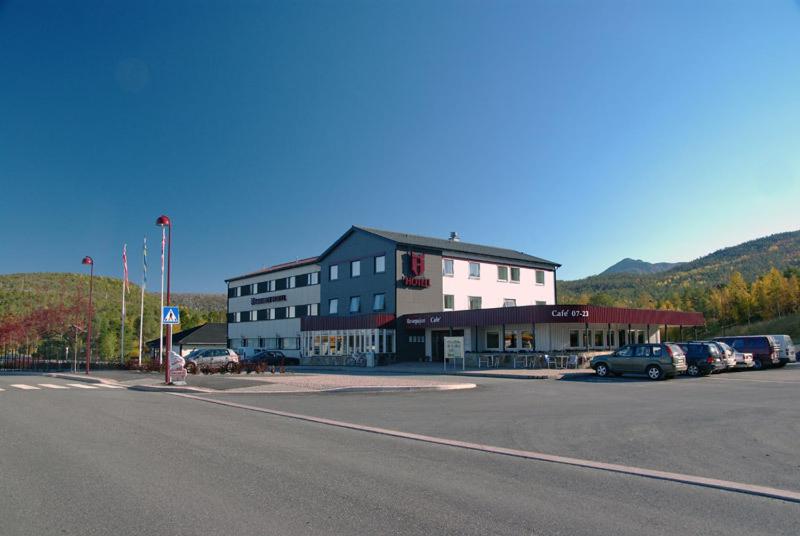 a large building with cars parked in a parking lot at Hamarøy Hotel in Innhavet