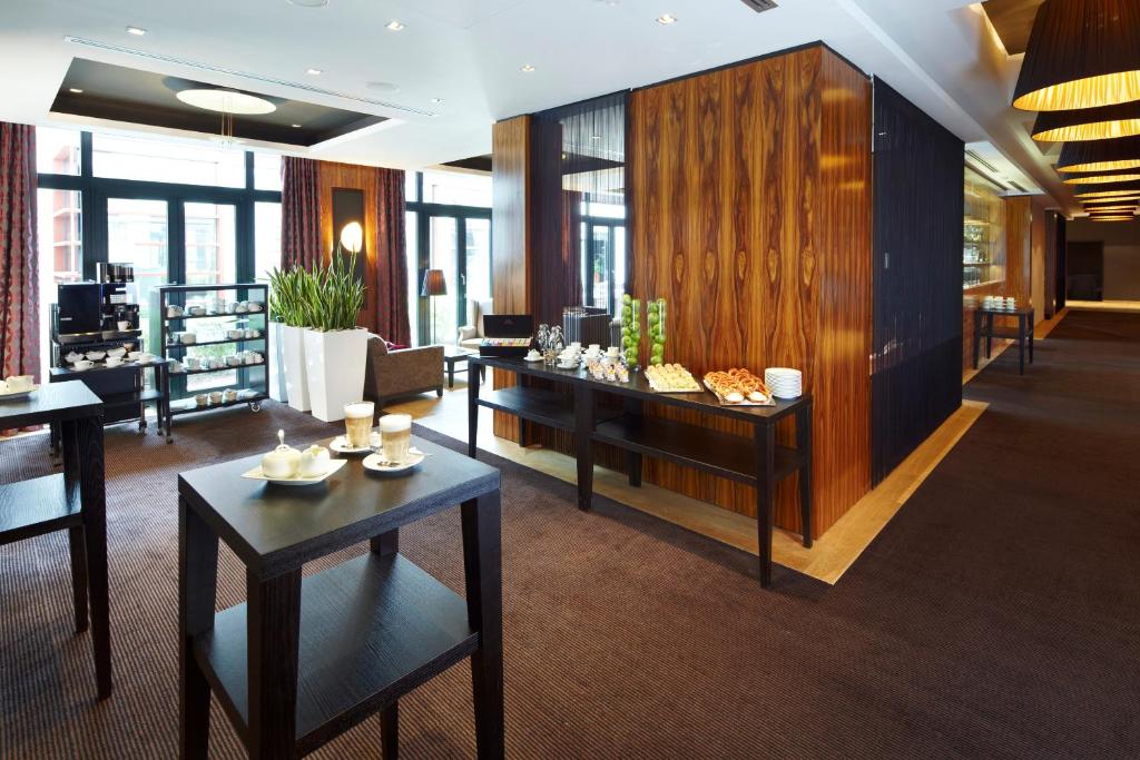 a lobby with tables and chairs in a building at Parkhotel Stuttgart Messe-Airport in Leinfelden-Echterdingen