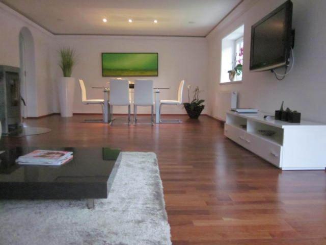sala de estar con mesa, sillas y TV en Appartement Bergblick II, en Faistenau