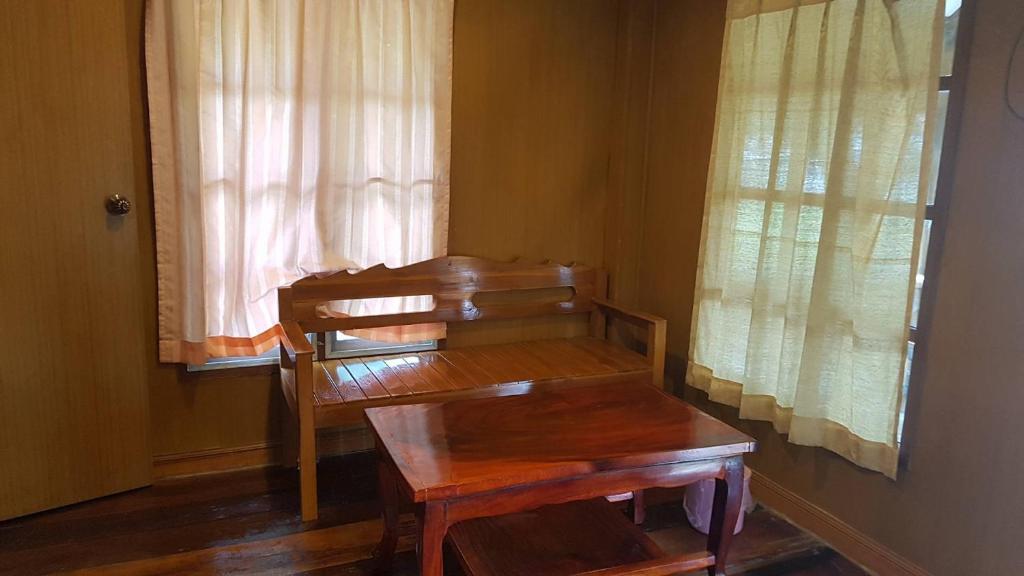 um banco de madeira num quarto com uma janela em U Thong Hotel em U Thong