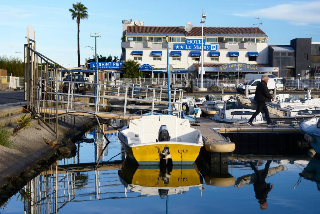 a man walking past a yellow boat in a marina at Le Maray in Le Grau-du-Roi