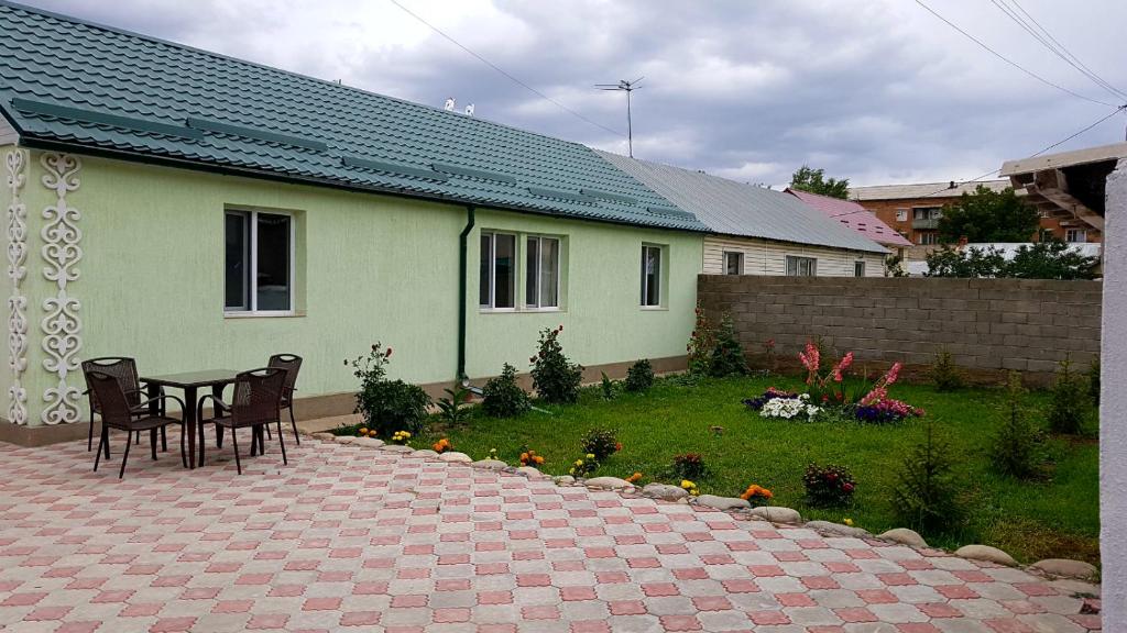 a patio with a table and chairs and a house at Datka Guest House in Naryn