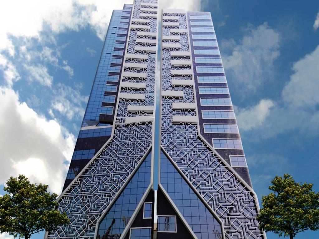 麥加的住宿－لمار أجياد الاول Tower A，一座高大的玻璃建筑,背后是蓝天