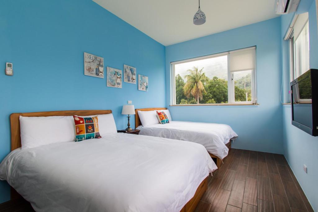 two beds in a room with blue walls and a window at ITSF B&B in Guanshan