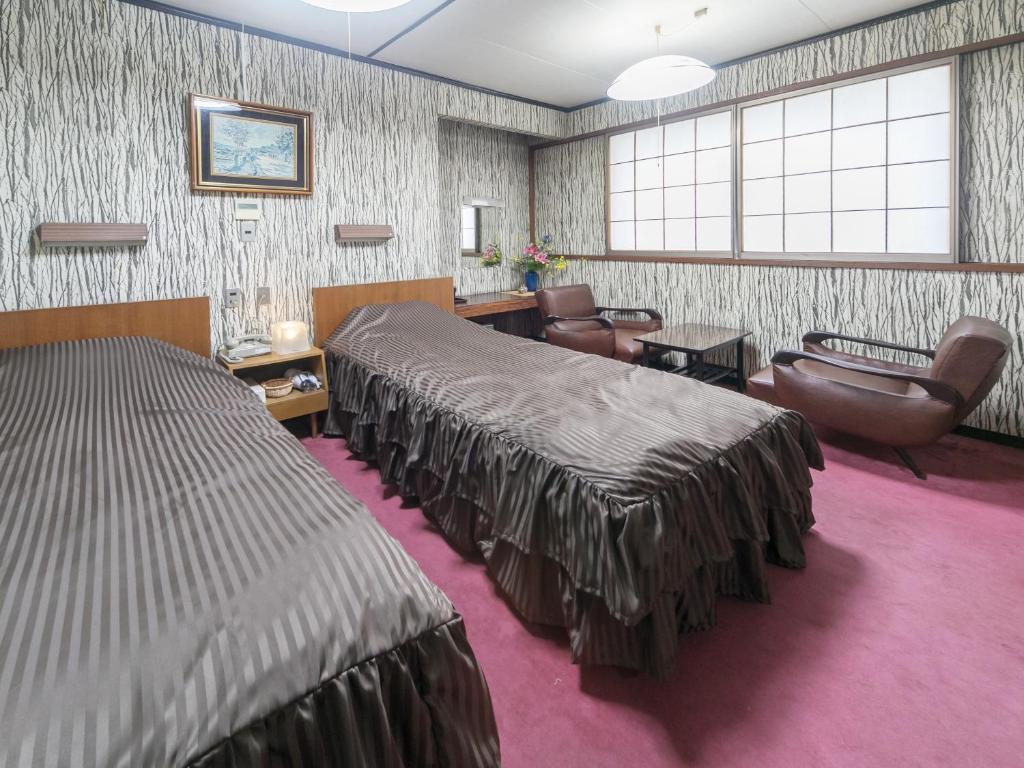 a hotel room with two beds and a waiting room at Riverside Hotel Shoei in Kochi