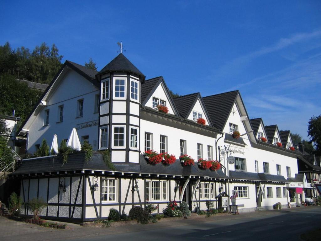 a white and black building with red flowers on it at Landhotel Menke in Brilon