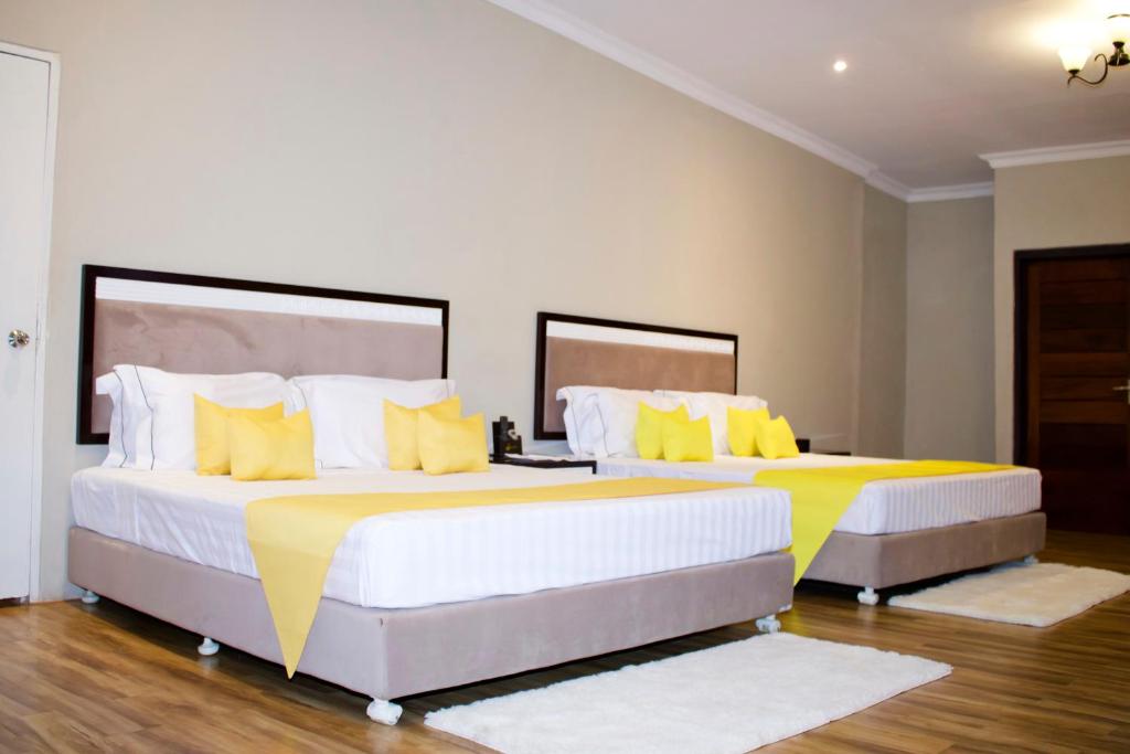 two beds with yellow pillows in a bedroom at Blue Waters by Serendib in Senga