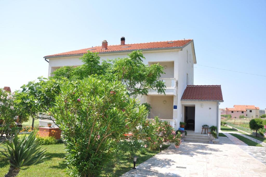 ein weißes Haus mit einem Baum davor in der Unterkunft Apartments Smilja in Ljubač